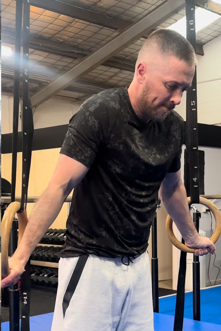 Photo of adults doing gymnastics strength training classes focused on strength training, mobility training, and skill training on gymnastics rings.