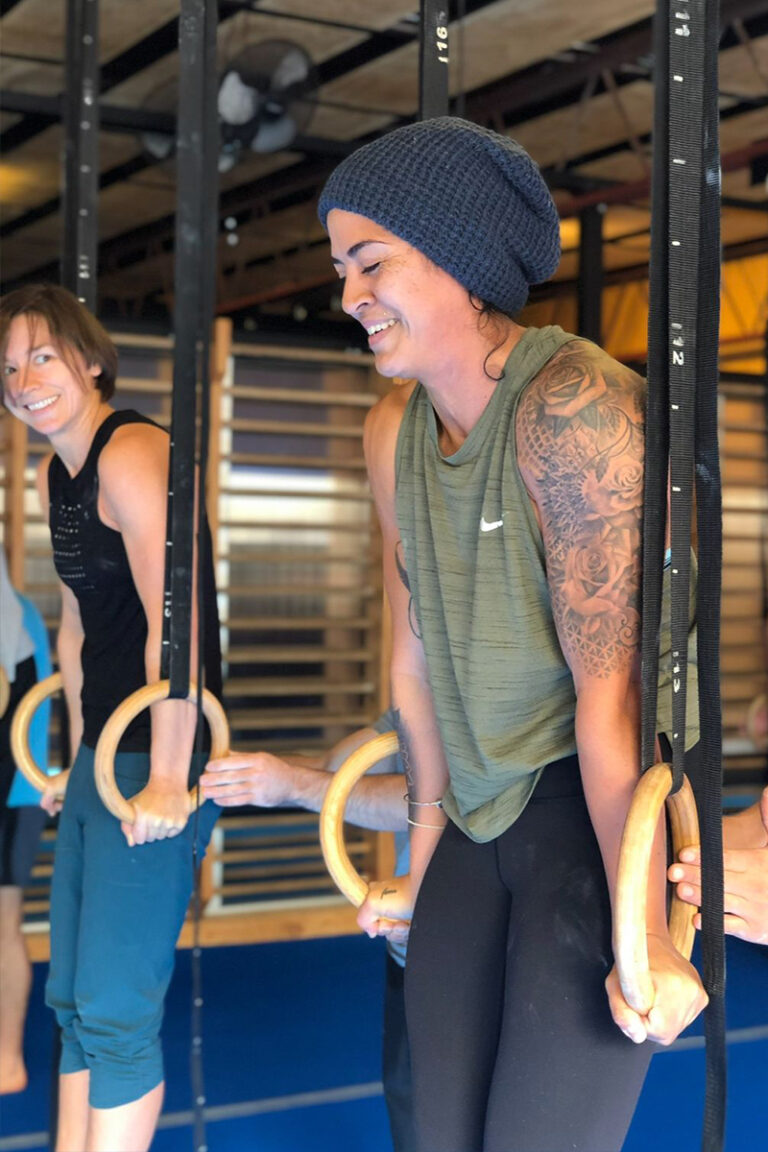 Photo of adults doing gymnastics strength training classes focused on strength training, mobility training, and skill training on gymnastics rings.